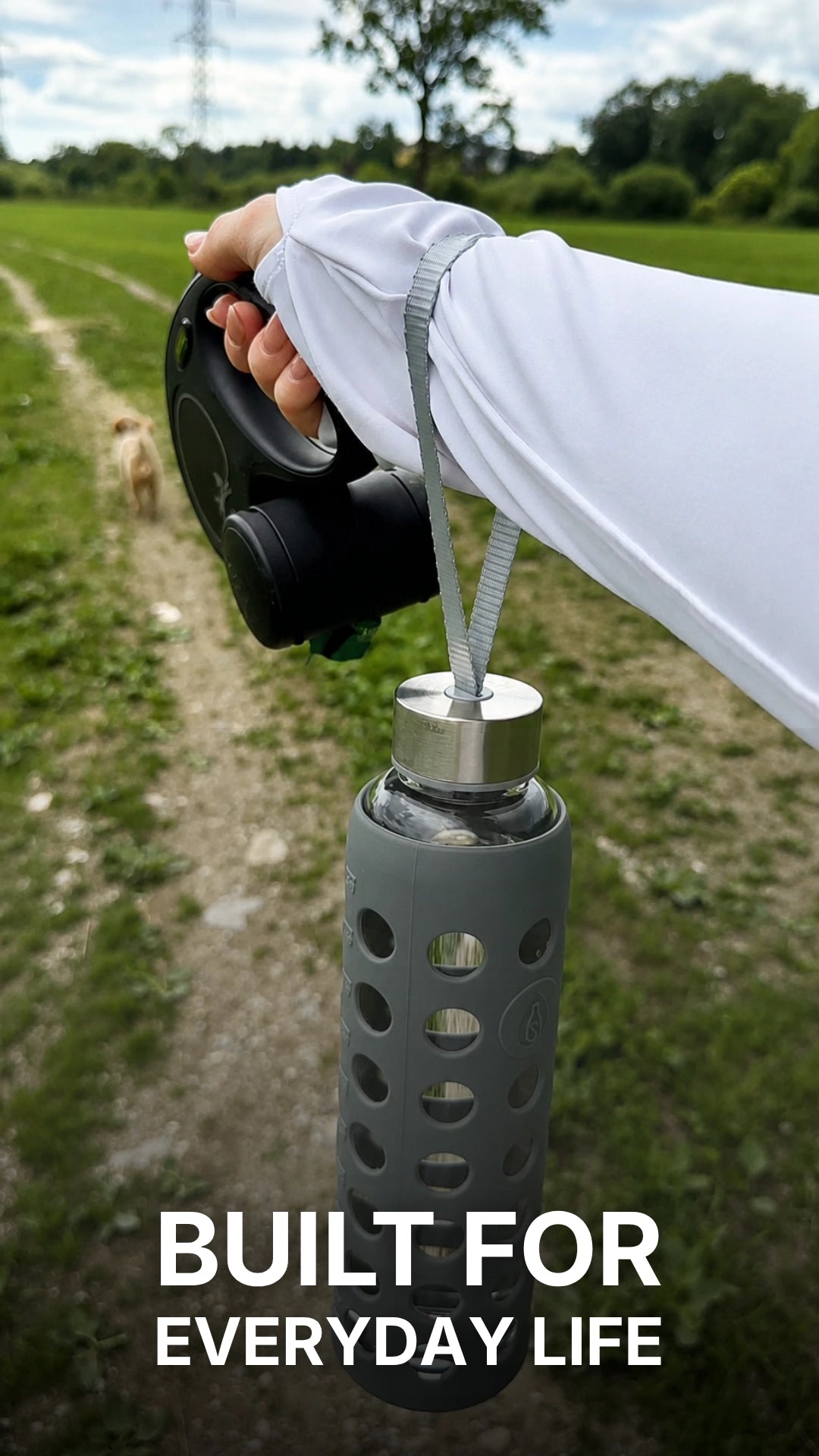 Load video: A woman stands in a grassy field and shares her experience with the spottle glass water bottle featuring a silicone sleeve. Close-up shots highlight the bottle, its wide drinking opening, and the practical carrying strap. She explains that the silicone sleeve provides a comfortable grip while adding extra protection for the glass bottle during everyday use. The video ends with a close-up of the bottle as she smiles and speaks positively to the camera.